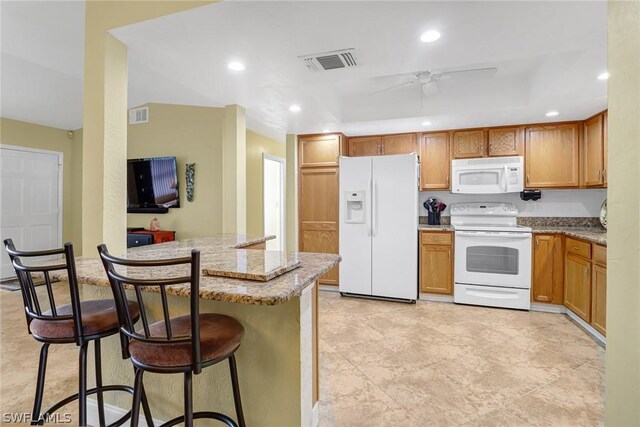 kitchen featuring a breakfast bar, visible vents, a ceiling fan, and white appliances
