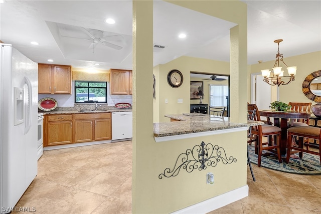 kitchen with ceiling fan with notable chandelier, white appliances, light stone counters, pendant lighting, and light tile floors