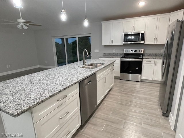 kitchen featuring stainless steel appliances, white cabinetry, a center island with sink, and sink