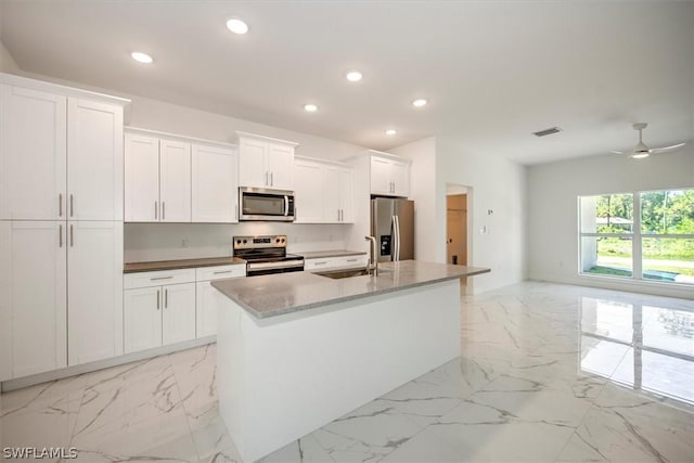 kitchen featuring appliances with stainless steel finishes, white cabinetry, a center island with sink, and sink