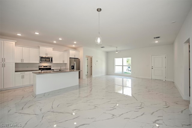 kitchen featuring a kitchen island with sink, appliances with stainless steel finishes, pendant lighting, and white cabinetry