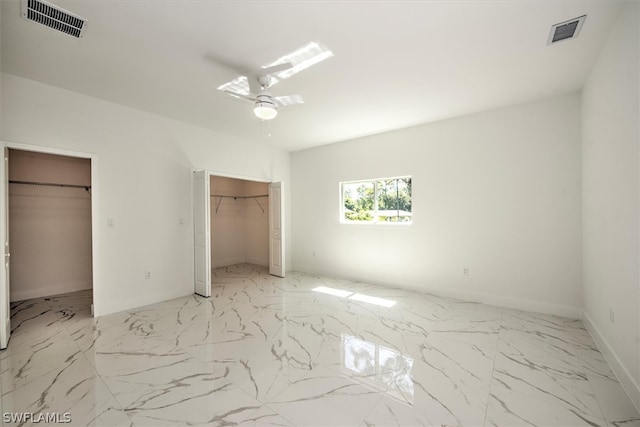 unfurnished bedroom featuring ceiling fan and a walk in closet