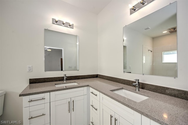 bathroom featuring toilet, ceiling fan, walk in shower, and vanity