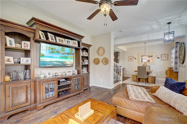 living room featuring ceiling fan with notable chandelier and dark hardwood / wood-style floors