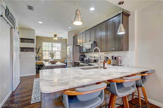 kitchen featuring ceiling fan, dark brown cabinetry, kitchen peninsula, and stainless steel refrigerator