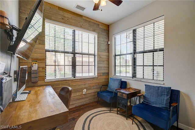 office with wood walls, ceiling fan, and a healthy amount of sunlight