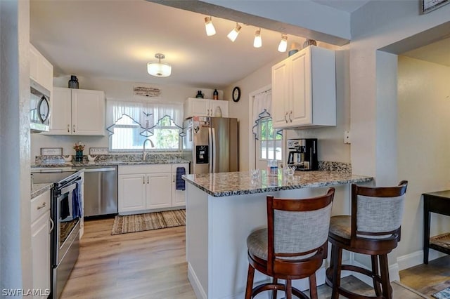 kitchen with white cabinets, sink, light hardwood / wood-style flooring, light stone counters, and stainless steel appliances