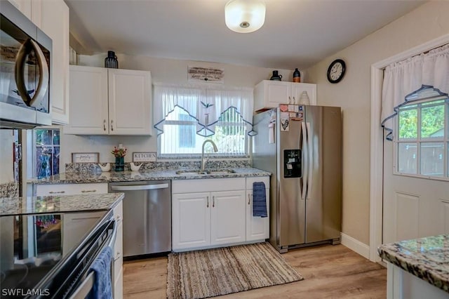 kitchen featuring white cabinetry, sink, light stone counters, and appliances with stainless steel finishes