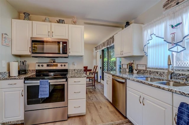 kitchen featuring white cabinetry, sink, light stone countertops, and appliances with stainless steel finishes