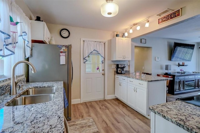 kitchen featuring white cabinetry, sink, light stone counters, and light wood-type flooring