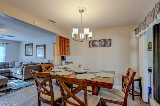 dining area featuring ceiling fan with notable chandelier and light hardwood / wood-style flooring