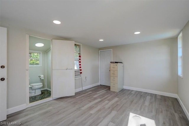 unfurnished bedroom featuring light wood-type flooring and connected bathroom