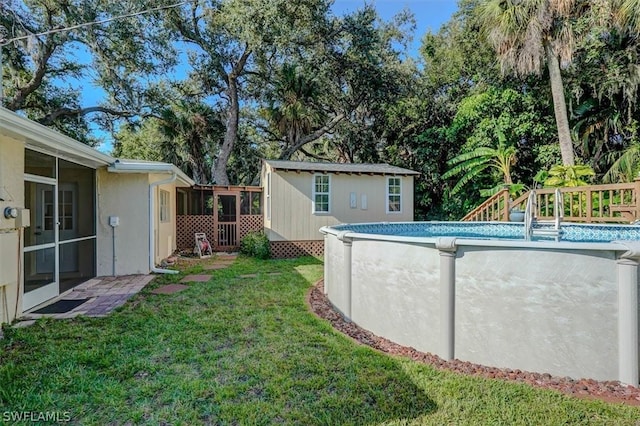 view of swimming pool featuring an outbuilding, a lawn, and a sunroom