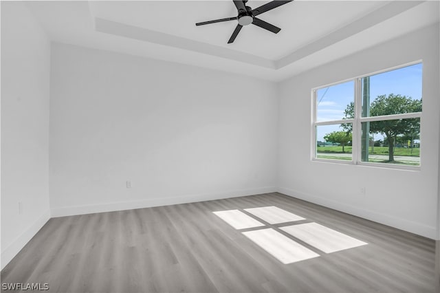 spare room featuring ceiling fan, a raised ceiling, and light hardwood / wood-style flooring