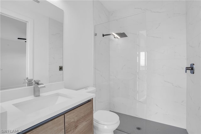 bathroom featuring vanity, toilet, and a tile shower