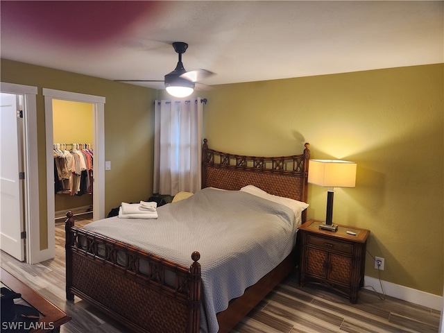 bedroom with ceiling fan, a closet, a walk in closet, and hardwood / wood-style flooring