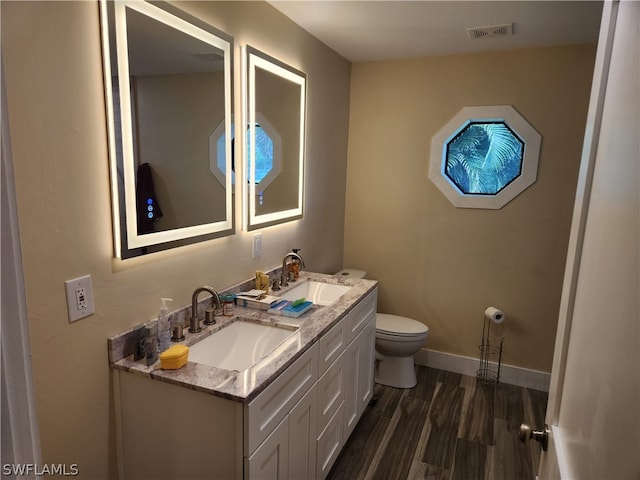 bathroom featuring hardwood / wood-style flooring, double vanity, and toilet