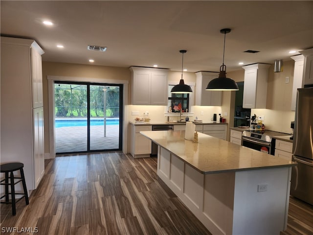 kitchen featuring white cabinets, dark hardwood / wood-style floors, a kitchen island, and stainless steel appliances