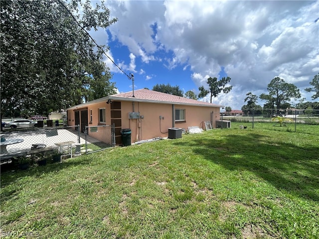 back of property featuring central AC and a lawn