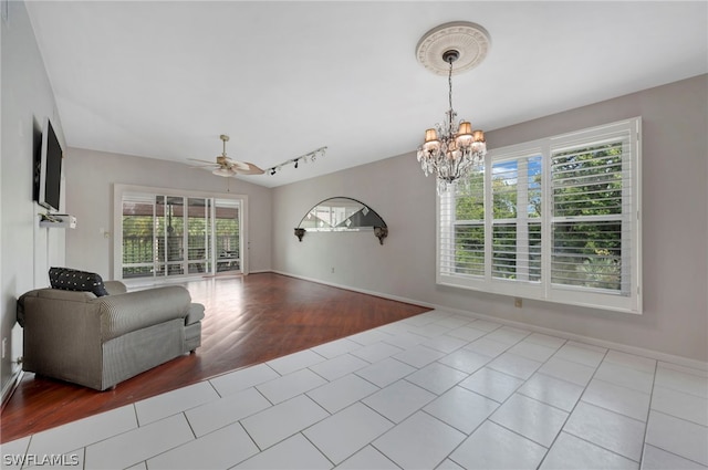 tiled living room featuring ceiling fan with notable chandelier and rail lighting