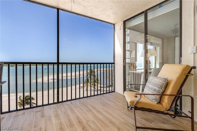 unfurnished sunroom with a water view and a beach view