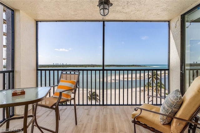 sunroom / solarium with a view of the beach and a water view