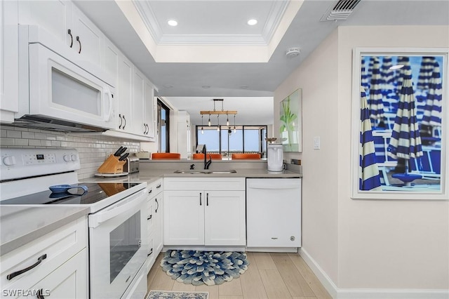 kitchen with sink, white appliances, a tray ceiling, white cabinets, and ornamental molding