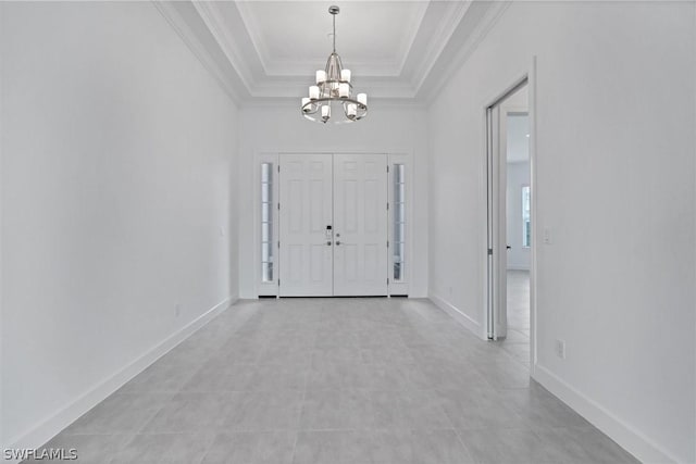 entryway featuring crown molding, light tile patterned floors, a raised ceiling, and a chandelier