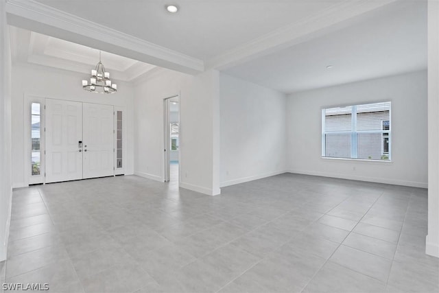 tiled foyer entrance with a raised ceiling, plenty of natural light, an inviting chandelier, and ornamental molding