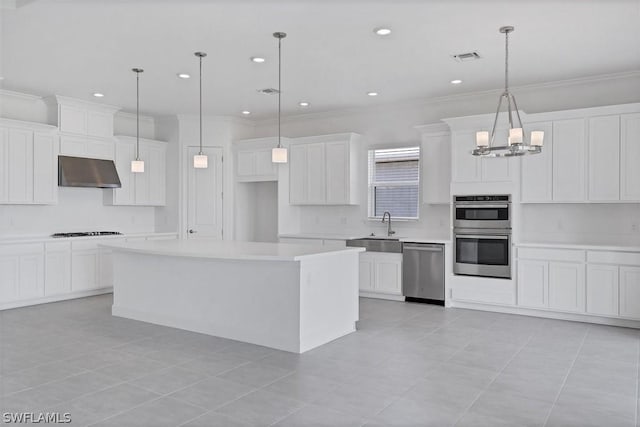 kitchen with stainless steel appliances, a center island, hanging light fixtures, white cabinets, and sink