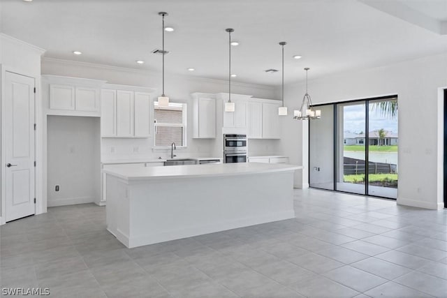 kitchen featuring a center island, a notable chandelier, pendant lighting, white cabinets, and sink