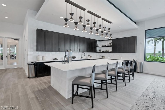 kitchen featuring a kitchen breakfast bar, sink, an island with sink, and pendant lighting