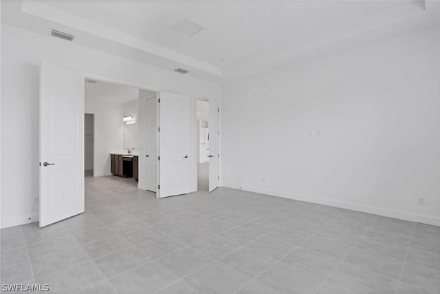 tiled empty room with a raised ceiling