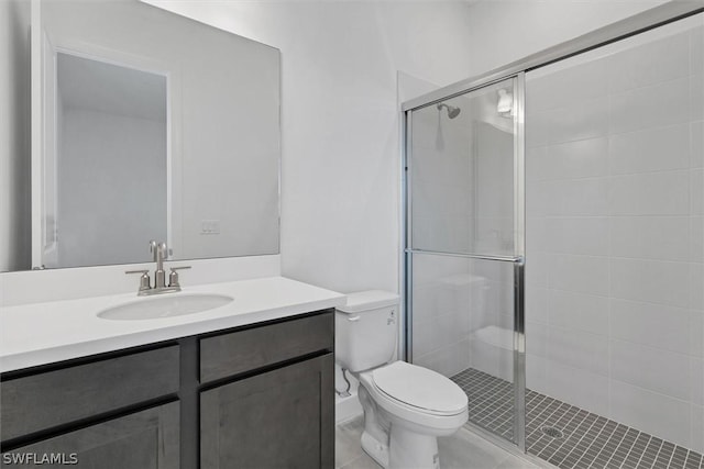 bathroom featuring toilet, a shower with door, tile patterned floors, and vanity