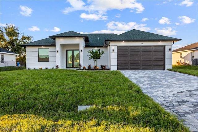 view of front facade featuring french doors, central AC, a garage, and a front lawn