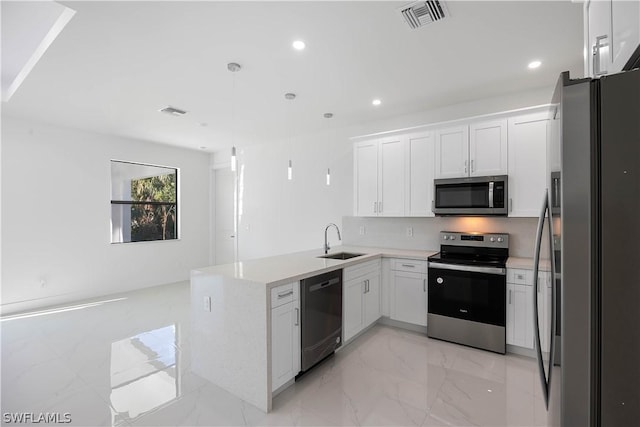 kitchen featuring kitchen peninsula, appliances with stainless steel finishes, sink, white cabinetry, and hanging light fixtures