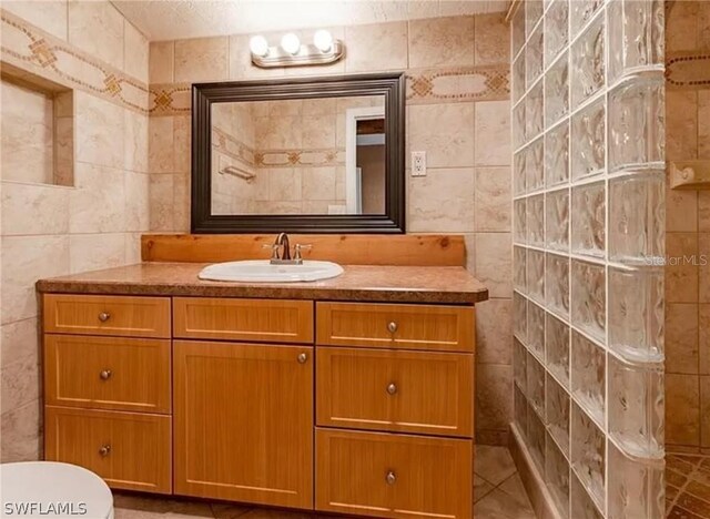 bathroom with tile flooring, tile walls, toilet, and vanity