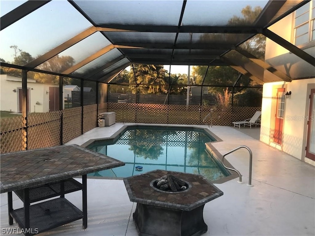 view of swimming pool with a patio, glass enclosure, and an outdoor fire pit