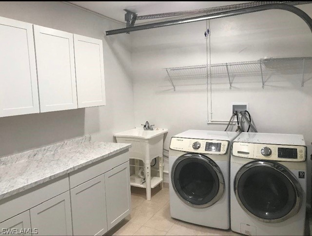 clothes washing area featuring hookup for a washing machine, washing machine and clothes dryer, cabinets, and light tile floors