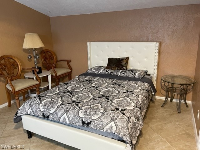 bedroom with vaulted ceiling, tile flooring, and a textured ceiling