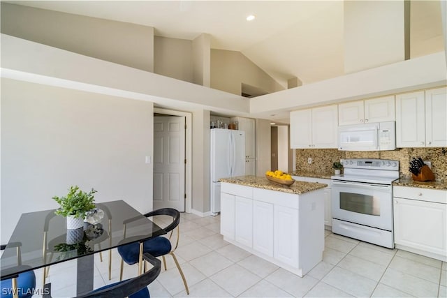 kitchen with white appliances, light stone countertops, tasteful backsplash, a kitchen island, and high vaulted ceiling