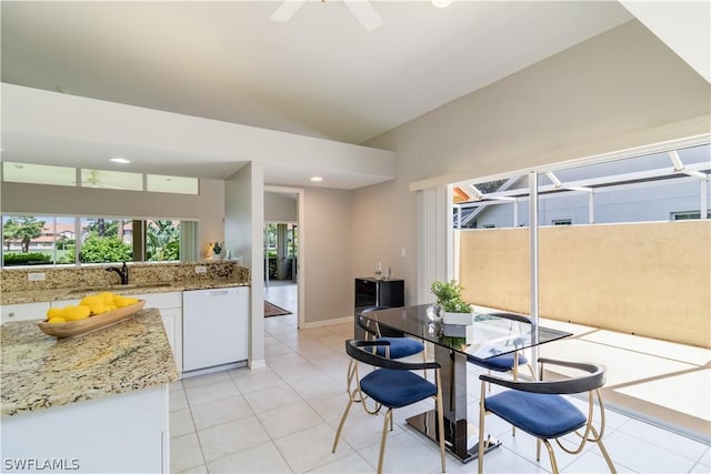 dining room with ceiling fan, sink, light tile patterned floors, and lofted ceiling