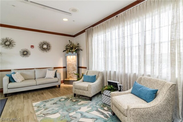 living area featuring light wood-type flooring and crown molding