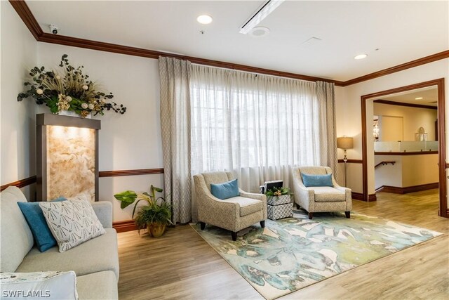 sitting room with hardwood / wood-style floors and crown molding