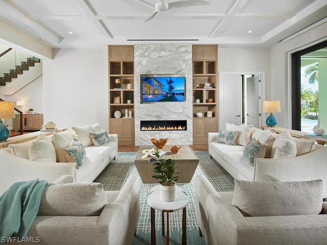 living room featuring coffered ceiling, hardwood / wood-style flooring, a fireplace, and built in features