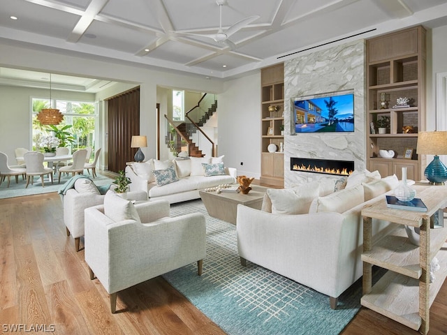 living room with coffered ceiling, built in shelves, and light hardwood / wood-style flooring