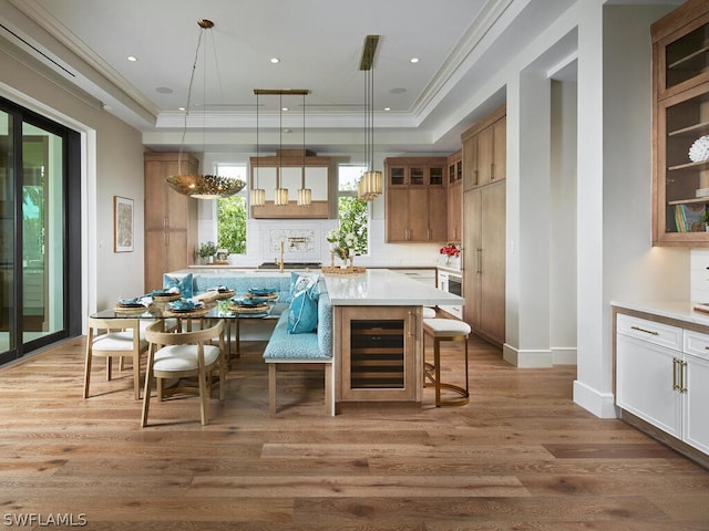 kitchen with a center island, tasteful backsplash, breakfast area, decorative light fixtures, and light wood-type flooring