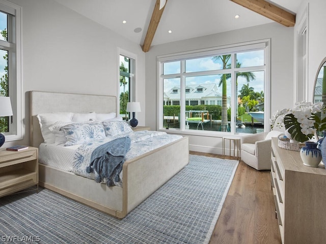 bedroom featuring beamed ceiling, wood-type flooring, and a water view