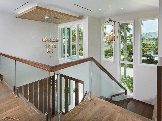 staircase with wood-type flooring, a chandelier, and a wealth of natural light