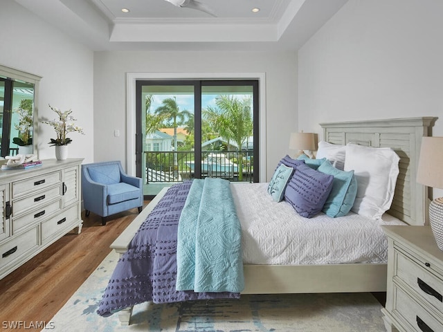 bedroom with a raised ceiling, ornamental molding, hardwood / wood-style flooring, and access to outside